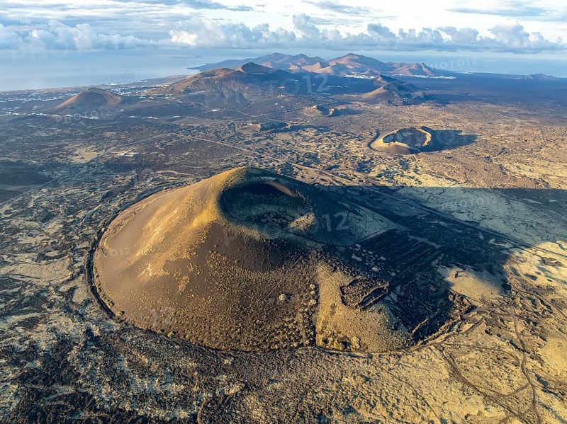 Montaña Negra volcano, picturesque volcanic landscape with volcanic craters and lava fields in morning light, Parque Natural de Los Volcanes, aerial view, Lanzarote, Canary Islands, Spain