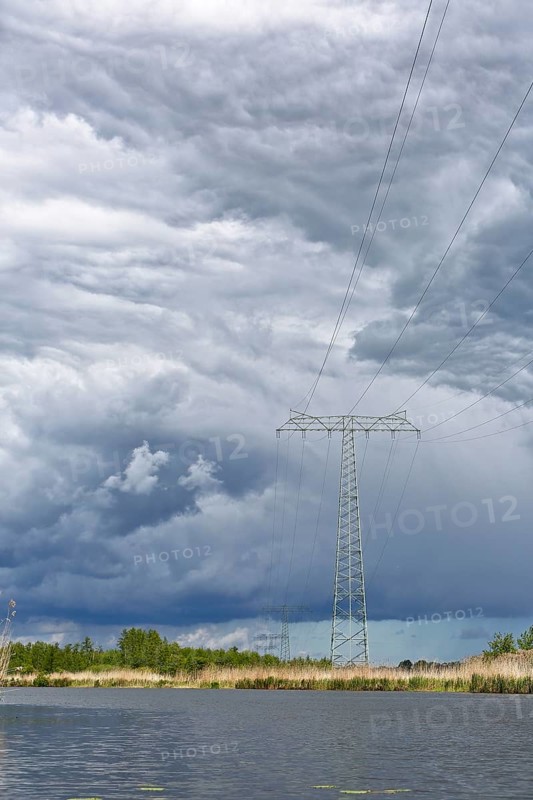 A large power pole in a vast landscape under dramatic clouds, Peenetal nature park Park, Mecklenburg-Western Pomerania, Germany