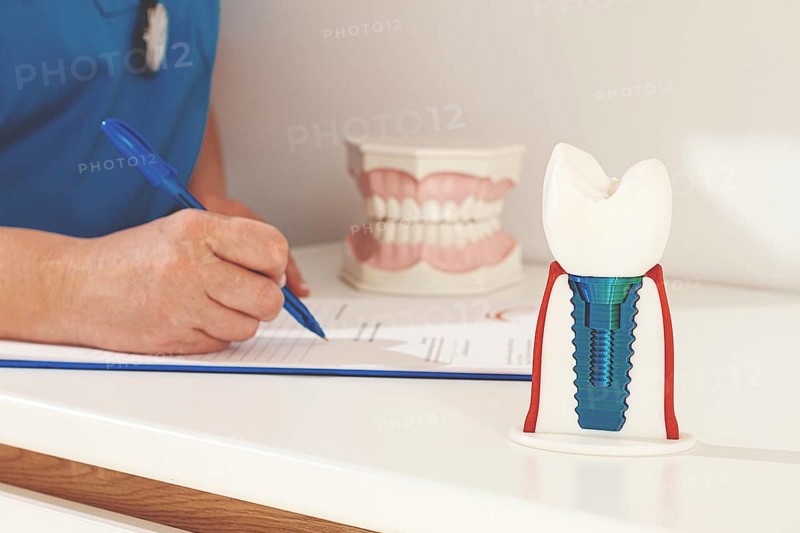 A dentist in a blue uniform studies patient information and prepares for treatment in a modern dental office