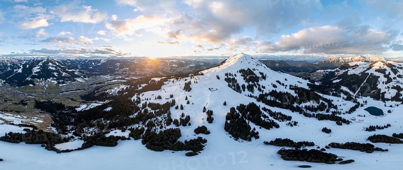 Sunset, alpine panorama, fantastic winter landscape with Hohe Salve, blue sky and snow, mountains and mountain valley, aerial view Skiwelt Wilder Kaiser ski area, Brixental, Tyrol, Austria