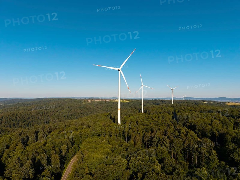 A series of wind turbines on a wooded hill under a wide blue sky, near Schorndorf, Remstal, Baden-Württemberg, Germany