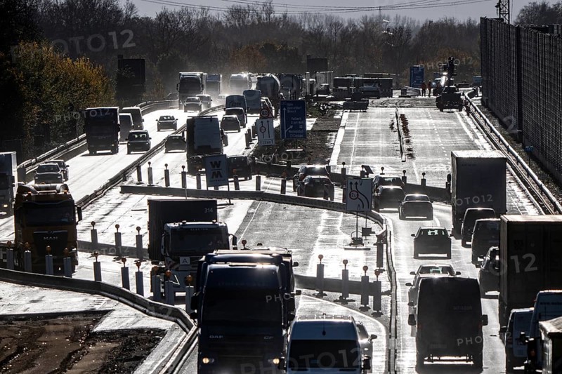 Highway construction site, the A57 is extended to 6 lanes on the section between the Meerbusch motorway junction and the Oppum junction, traffic runs parallel to 2 narrowed lanes, wet road after rain shower, Krefeld, North Rhine-Westphalia, Germany