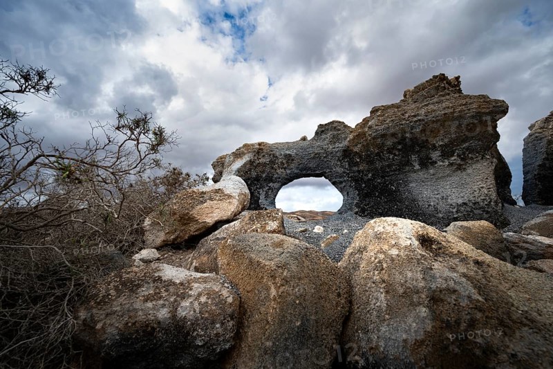 Eroded rock formations with rock tunnels, volcanic landscape with dramatic cloudy skies, Ciudad Estratificada or Los Roferos, Antigua Rofera de Teseguite, Lanzarote, Canary Islands, Spain