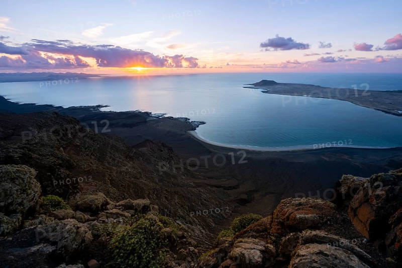 View from steep cliffs to sea and coast with sun stars, Mirador del Porrito viewpoint at sunset, Lanzarote, Canary Islands, Spain