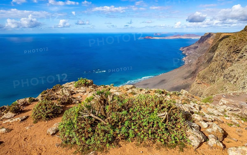 View from the Castillejo viewpoint from the Risco de Famara cliffs to the coast and the sea with the Famara beach, Playa de Famara, Lanzarote, Canary Islands, Spain