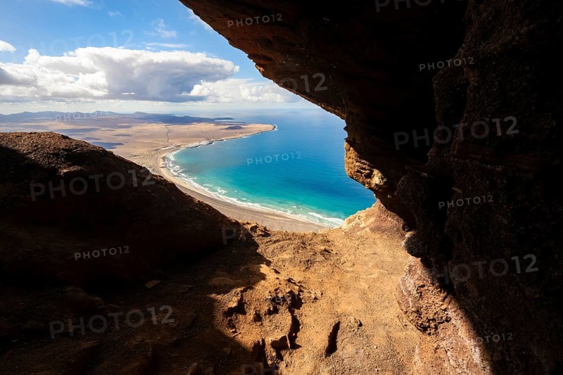 Cueva de las Cabras cave, view from the Risco de Famara cliffs on Famara beach, Playa de Famara with La Calaeta, Lanzarote, Canary Islands, Spain