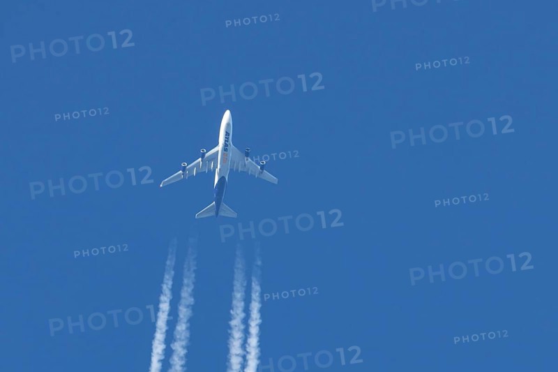 Boeing 747 jumbo jet cargo aircraft of Atlas air airlines flying in a blue sky with contrails or vapour trails behind, England, United Kingdom
