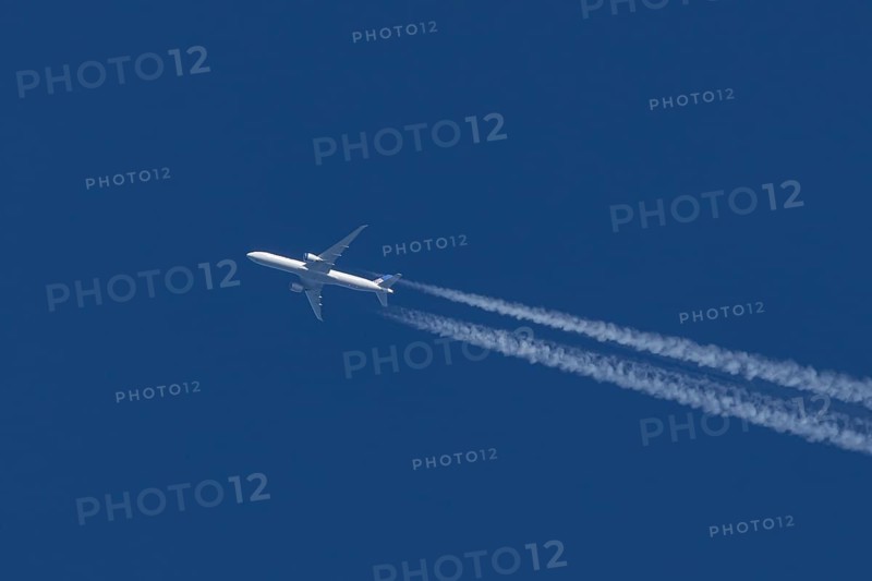 Boeing jet passenger aircraft of United airways airlines flying in a blue sky with contrails or vapour trails behind, England, United Kingdom