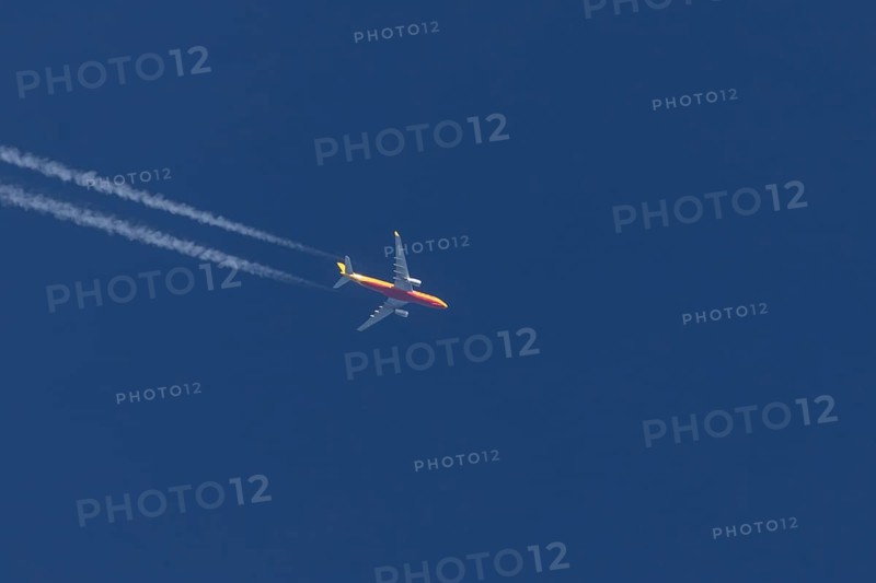 Boeing 767 jet cargo aircraft of DHL airlines flying in a blue sky with contrails or vapours trails behind, England, United Kingdom