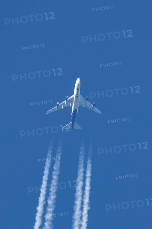 Boeing 747 jumbo jet cargo aircraft of Atlas air airlines flying in a blue sky with contrails or vapour trails behind, England, United Kingdom