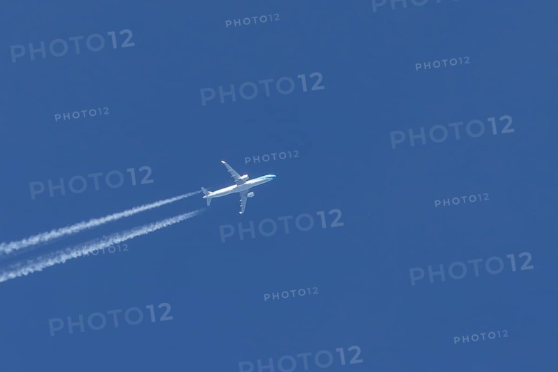 Jet passenger aircraft flying in a blue sky with contrails or vapour trails behind, England, United Kingdom