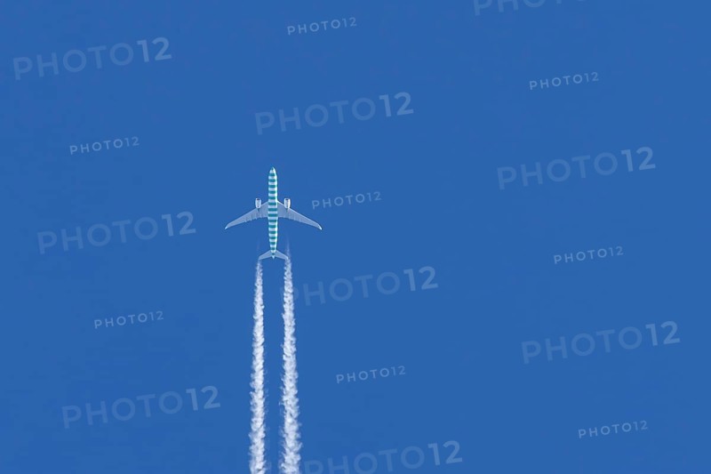 Boeing jet passenger aircraft flying in a blue sky with contrails or vapour trails behind, England, United Kingdom