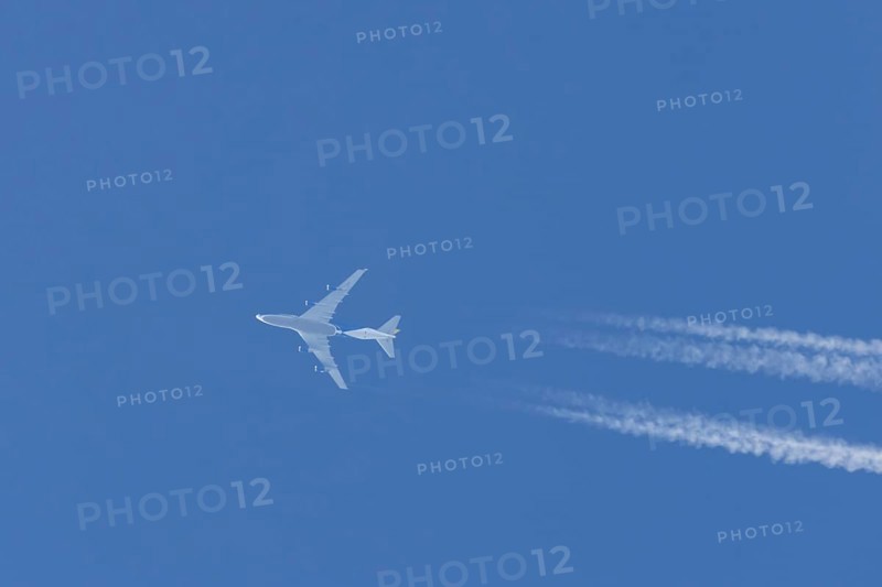 Boeing 747 jumbo jet cargo aircraft flying in a blue sky with contrails or vapour trails behind, England, United Kingdom