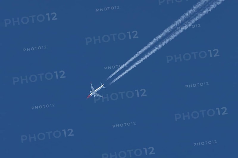 Boeing 737 jet passenger aircraft of Norwegian Air airlines flying in a blue sky with contrails or vapour trails behind, England, United Kingdom