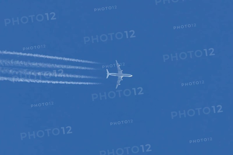 Jet commercial passenger aircraft flying in a blue sky with contrails or vapour trails behind, England, United Kingdom