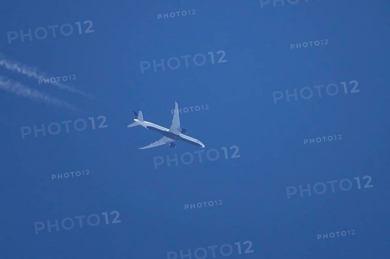 Boeing jet passenger aircraft flying in a blue sky with contrails or vapour trails behind, England, United Kingdom