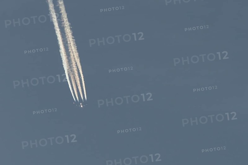 Jet passenger aircraft flying in a blue sky with contrails or vapour trails behind, England, United Kingdom