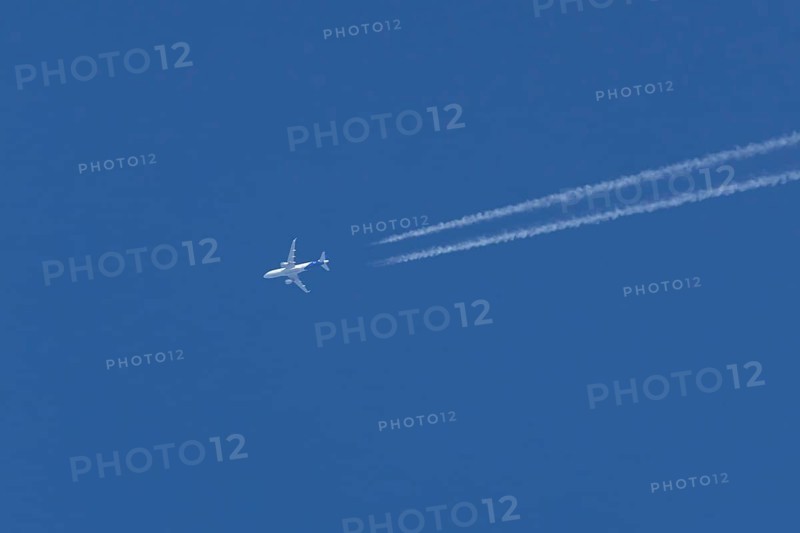 Airbus jet passenger aircraft flying in a blue sky with contrails or vapour trails behind, England, United Kingdom
