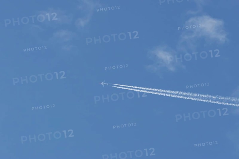 Boeing 737 jet passenger aircraft of Norwegian Air airlines flying in a blue sky with contrails or vapour trails behind, England, United Kingdom