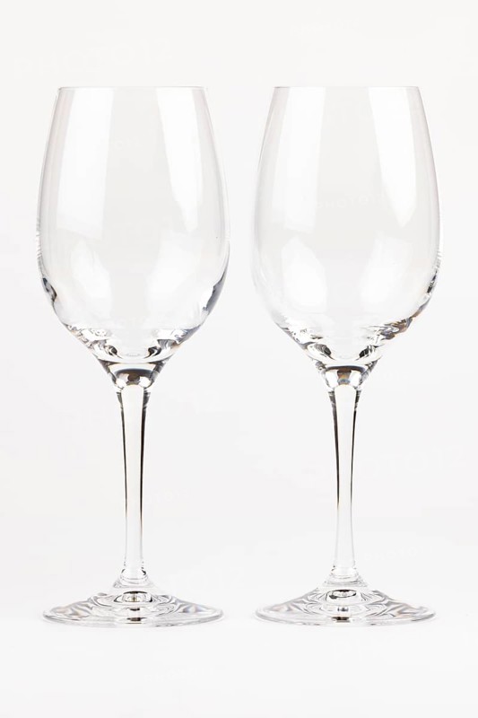 Two elegant, transparent wine glasses with long stems next to each other