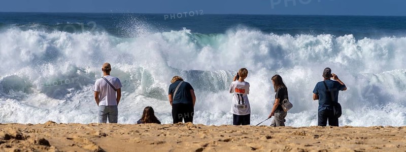 Tourists watch the waves of the Atlantic on the rocky plateau of Sito, also known as Forte São Miguel, a surfing paradise with monster waves in the months of November to February, Nazaré, Portugal