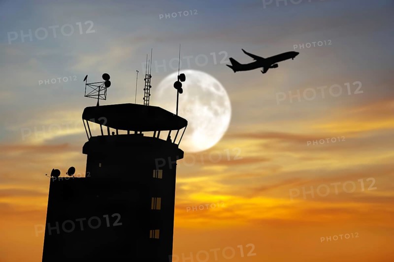 Air traffic control tower at airport as airplane takes off