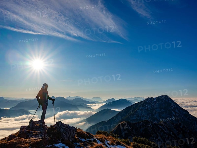 Mountaineer looking at blue-colored silhouette of mountains, fog in the valley, Hochstaufen, Chiemgau Alps, Upper Bavaria, Bavaria, Germany