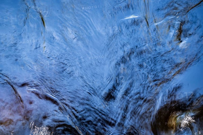 Shimmering blue water surface of a stream, current, light reflections, abstraction, long exposure, Sweden