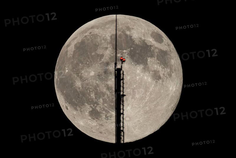 The full moon passes through the antenna on the roof of the European Central Bank (ECB), Frankfurt am Main, Hesse, Germany