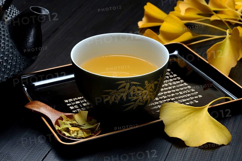 Ginkgo tea in tea bowl and ginkgo leaf, tea leaves in a spoon, ginkgo biloba