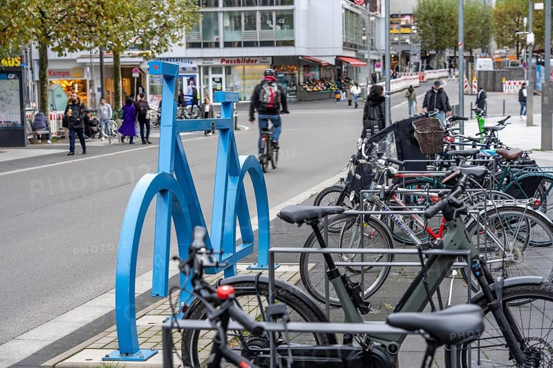 Bicycle parking spaces, with so-called leaning bars and a large blue bicycle silhouette, to make parking spaces visible at Bochum City Hall, North Rhine-Westphalia, Germany