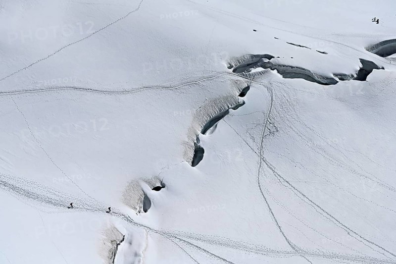 A group of mountaineers runs across a snow-covered mountain, Aiguille du Midi, Chamonix-Mont-Blanc, Haute-Savoie, France