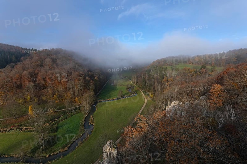 Autumn landscape with rising fog over the Grosse Lauter river loop in Lautertal at sunrise. View from above of the picturesque valley with colorful deciduous forest and rolling hills, Großes Lautertal, Baden-Württemberg, Germany