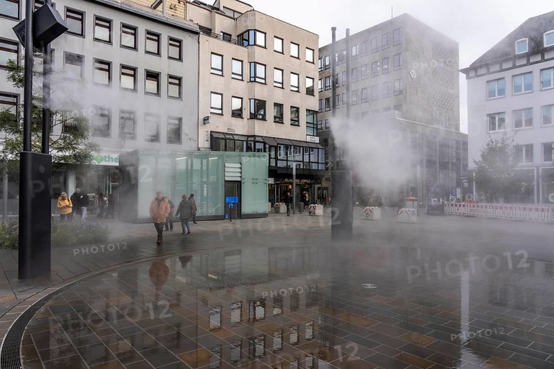 Digital water feature, Blue Cloud water installation on Husemanplatz in downtown Bochum, water mist is sprayed from 4 metal masts, which, in conjunction with the circular water surface, is intended to cool the surrounding area when it is hot, colored light images are projected into the water mist via projectors, part of the transformation of Husemanplatz