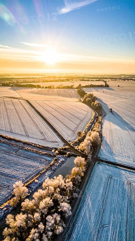 Bird Eye Perspective of Frost Covered Farmland. Seasonal Agricultural Scenery, winter and autumn scene, blue sky with golden light at sunrise, AI generated