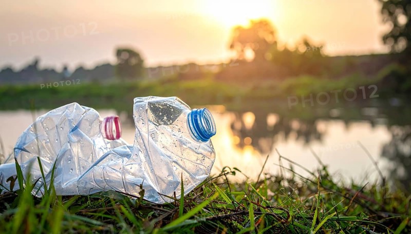 Crushed plastic water bottle waste in a wild landscape, symbol for nature protection, waste avoidance, recycling and ecology concepts on earth environment, AI generated