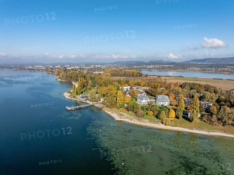 Aerial view of the Mettnau peninsula, surrounded by autumn vegetation, in western Lake Constance with the spa center, Mettnaukur, boat dock and restaurant Strandcafe, Radolfzell, Konstanz district, Baden-Württemberg, Germany