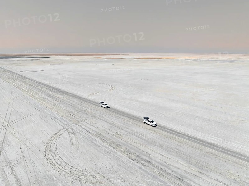 Aerial view, two off-road cars driving on a salt pan, arid landscape, Botswana