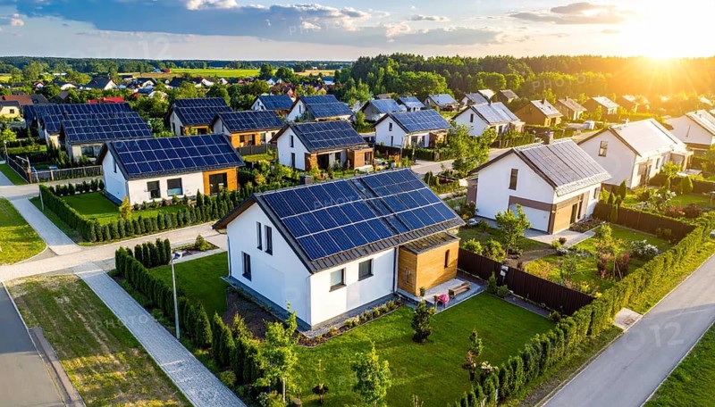 Aerial view showcases modern houses with solar panels and green roofs in a suburban setting, vibrant sunrise with blue sky, AI generated