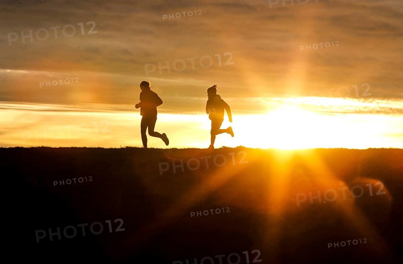 Woman and child walk across a dike on the island of Fehmarn at sunset, 13.10.2025, Fehmarn, Schleswig-Holstein, Germany