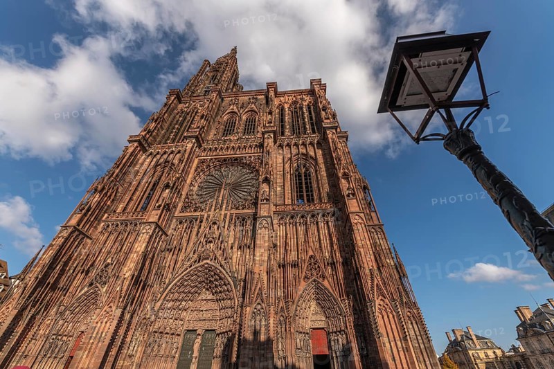 Strasbourg's Notre Dame Cathedral stands majestically there. Its magnificent architectural details are clearly visible under the blue, cloudy sky. Bas Rhin, Alsace, France