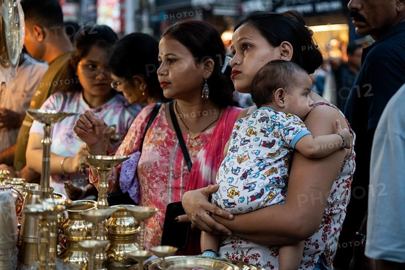 People shop for bronze and other metal items at a roadside stall on Dhanteras, in Guwahati, Assam, India on 18 October 2025. On Dhanteras, people traditionally buy precious metals like gold, silver, or even new utensils, as it is believed this brings wealth and good luck into the household