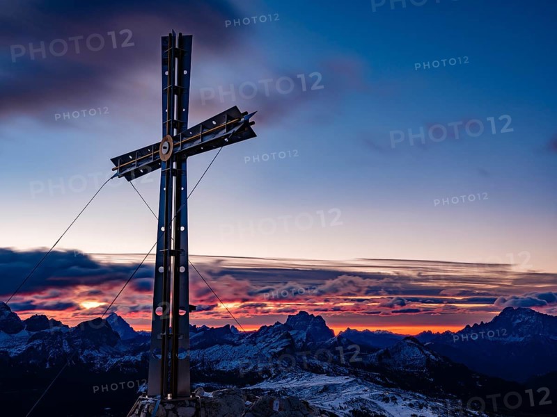 Sassongher summit cross at dawn, in the background Monte Cristallo, Monte Pelmo and Civatta, Dolomites, Trentino, South Tyrol, Italy