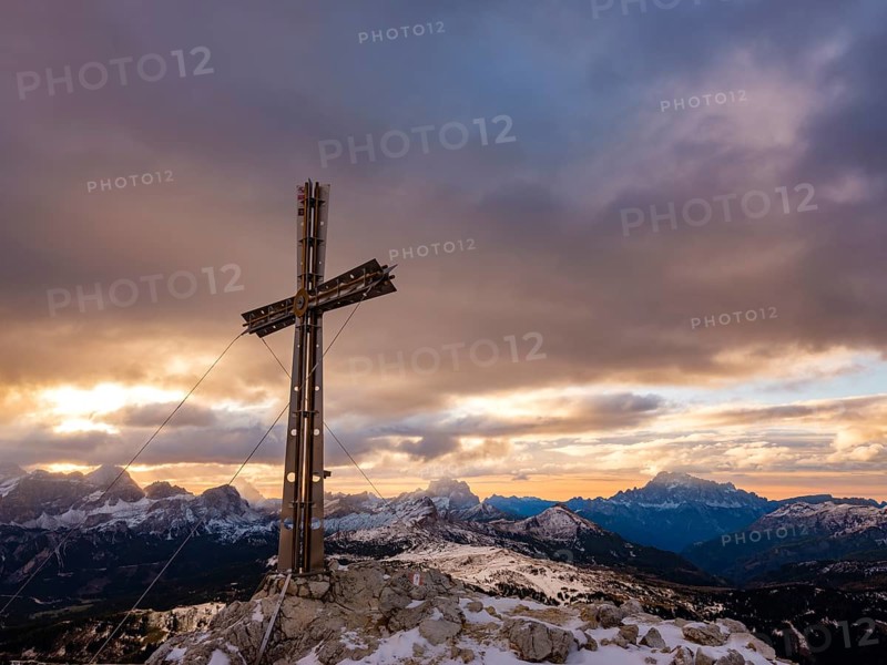 Sassongher summit cross at sunrise, in the background Monte Cristallo, Monte Pelmo and Civatta, Dolomites, Trentino, South Tyrol, Italy