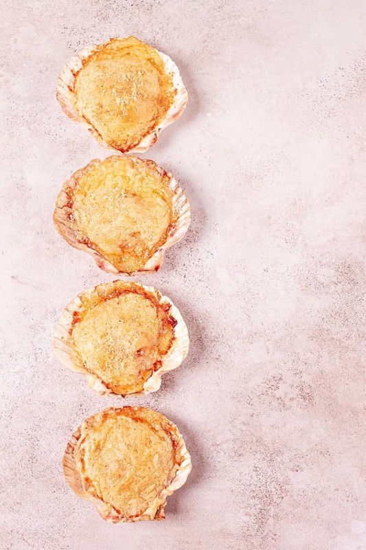Scallop, baked in shells, with cheese and spices, on the table, homemade