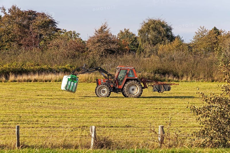 Tractor transporting bales of silage wrapped in film, Falshöft, Pommerby, Schleswig-Holstein, Germany