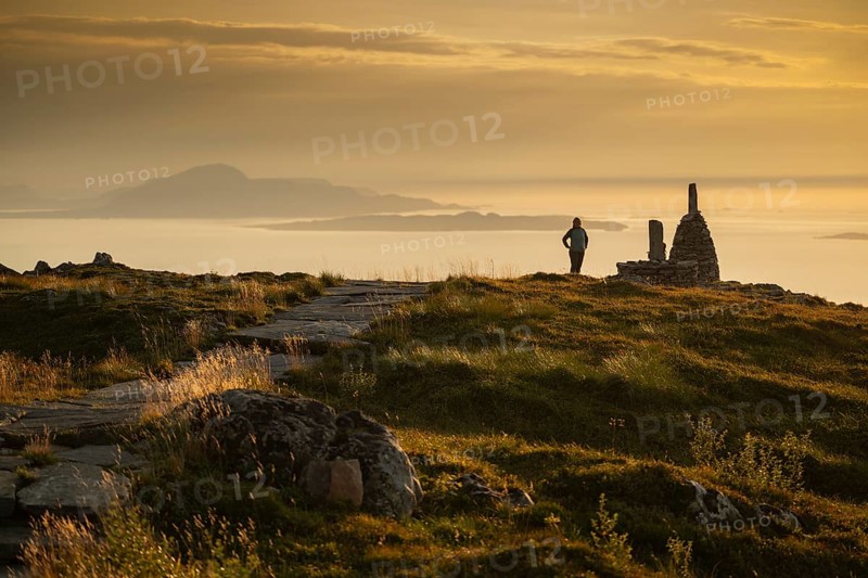 Woman standing next to cairn and looking at the sea, Rørsethornet stone staircase, with 3292 steps one of the longest continuous stone staircases in the world, Sherpat stairs or Midsund stairs or Midsundtrappene, Rørsethornet hike, evening mood, Otroya or Otrøya island, Møre og Romsdal, Norway