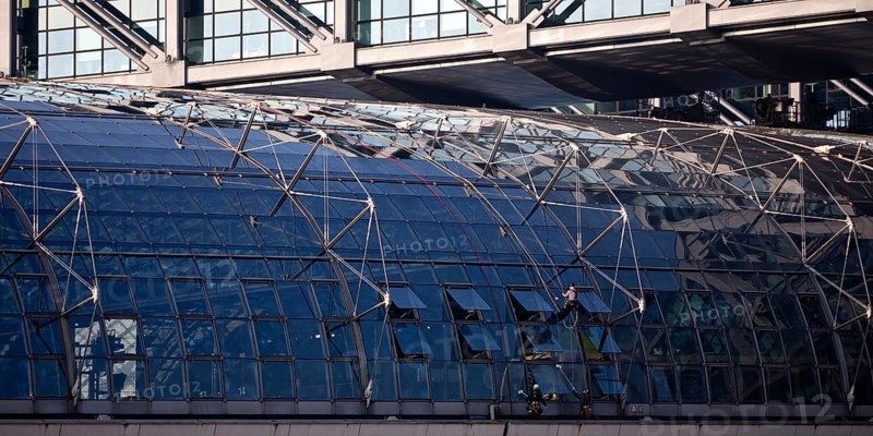 Three male glass cleaners cleaning a glass roof at Berlin Central Station, Berlin, Germany