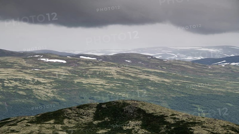 Vast mountain landscape with patches of snow and a cloudy atmosphere, pilgrimage route Olavsweg or Olavsleden, old Kongevegen or King's Path over Dovrefjell, Norway