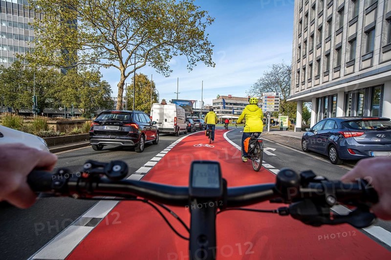 Riding a bike in a bike lane, marked in red to attract the attention of motorists, between 2 lanes, Huyssenallee, in front of Europaplatz, in the city centre of Essen, North Rhine-Westphalia, Germany
